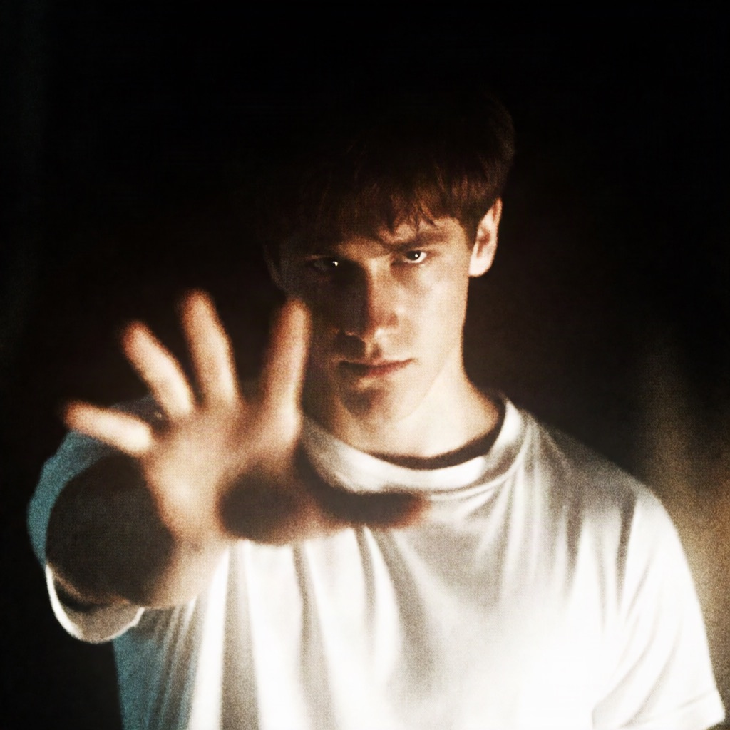 Cinematic low-light portrait of a young man reaching a hand toward the camera